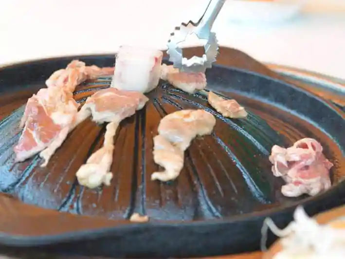 ラム肉を焼いている写真です。真ん中が盛り上がったドーム状の部分で肉を焼いています。
