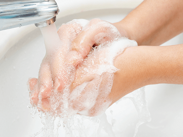 手洗いをしている写真です。石けんを泡立てて流水で手を洗っています。