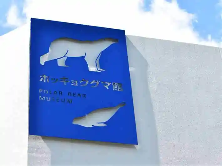 丸山動物園のホッキョクグマ館の外観です。白い建物です。青い看板にはホッキョクグマとアザラシの姿が描かれています。
