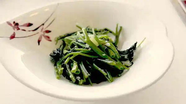 「空心菜の葱生姜炒め」の写真です。白い器に盛られた鮮やかな緑色の空芯菜がもられています。
