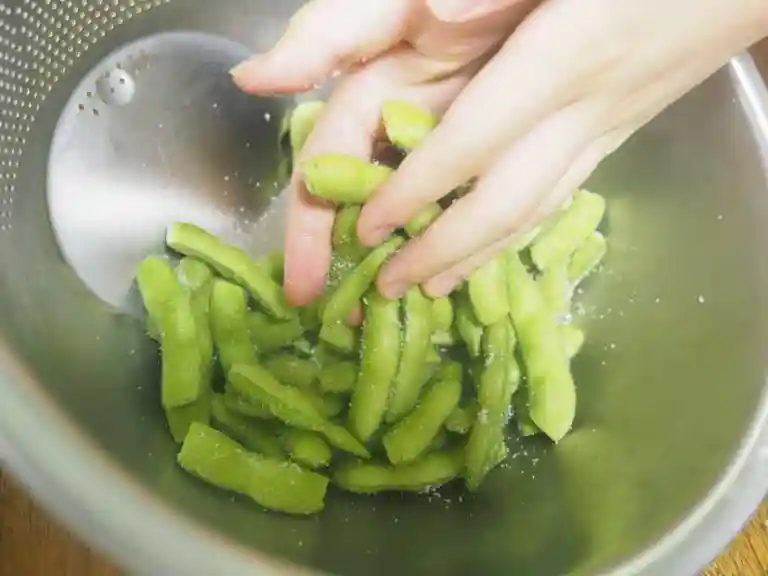 枝豆に塩をかけて、手で塩を枝ママに揉み込みます。塩味が枝豆にしみこみ、茹であがりが鮮やかな緑色になります。
