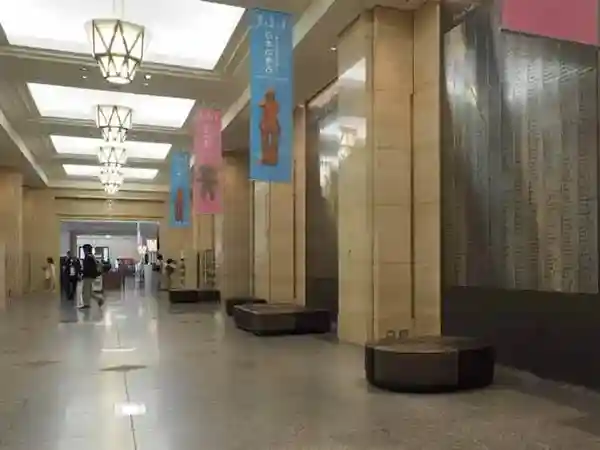 This photo shows a row of brown sofas lined up in front of the Archaeological Exhibition Room at the Heiseikan. The room boasts a high ceiling adorned with sturdy marble pillars, with sofas placed between the pillars.