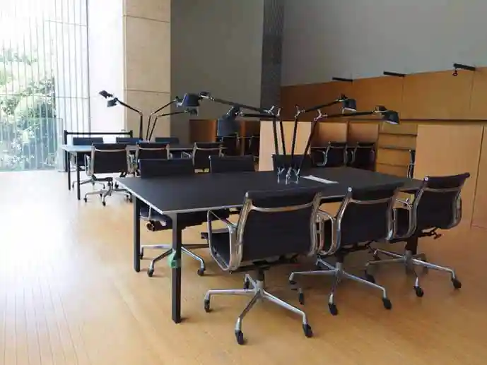 法隆寺宝物館2階の資料室に備えられた机と椅子の写真です。1台の机に6脚の椅子と3個のライトが備えられています。机と椅子、ライトはすべて黒色です。