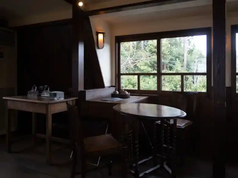 This photo shows a room on the second floor of Café Shinkokan. The room is dimly lit and has a fantastic atmosphere. Trees in the garden can be seen from the window.