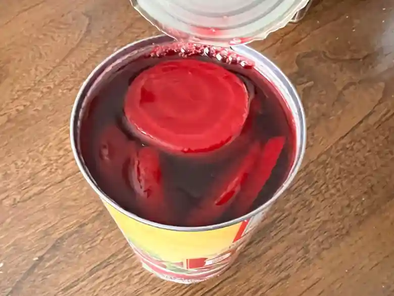 ビーツの缶詰の蓋を開けた写真です。鮮やかな赤色をしたビーツがスライスされて赤い汁の中に沈んでいます。