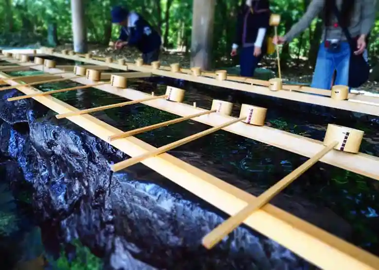 This photo shows the Temizusha at Naiku of Ise Grand Shrine. Temizu is a ritual to purify oneself by washing hands and rinsing the mouth with clean water before entering the main shrine. The Temizusha is a place containing a pool of water for use in ritual purification. Worshippers use a dipper to scoop water from the Temizusha and purify their hands and mouths with the water.