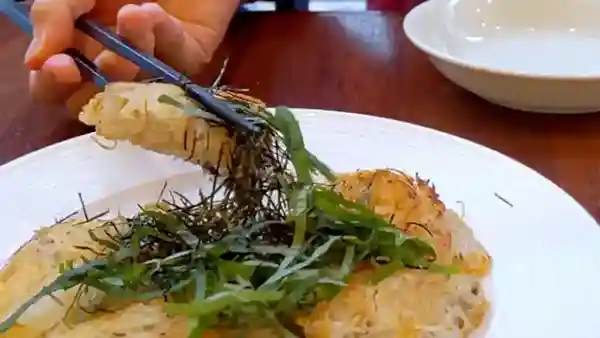 This picture shows a baked "potato noodles" dish with whitebait, approximately 20 cm in diameter, and garnished with chopped green shiso and nori seaweed.