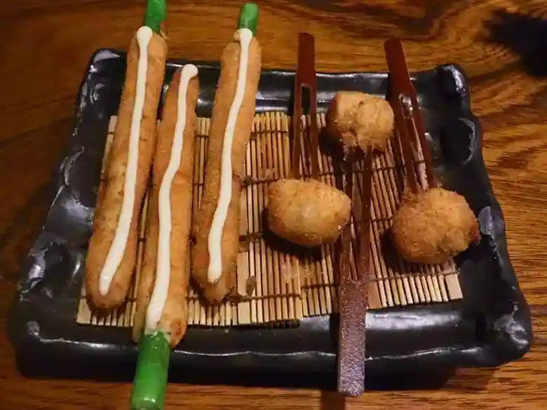 This photo shows the fourth plate of Kushiage: three asparagus Kushiage and three tomato KKushiage served on a brown square plate.