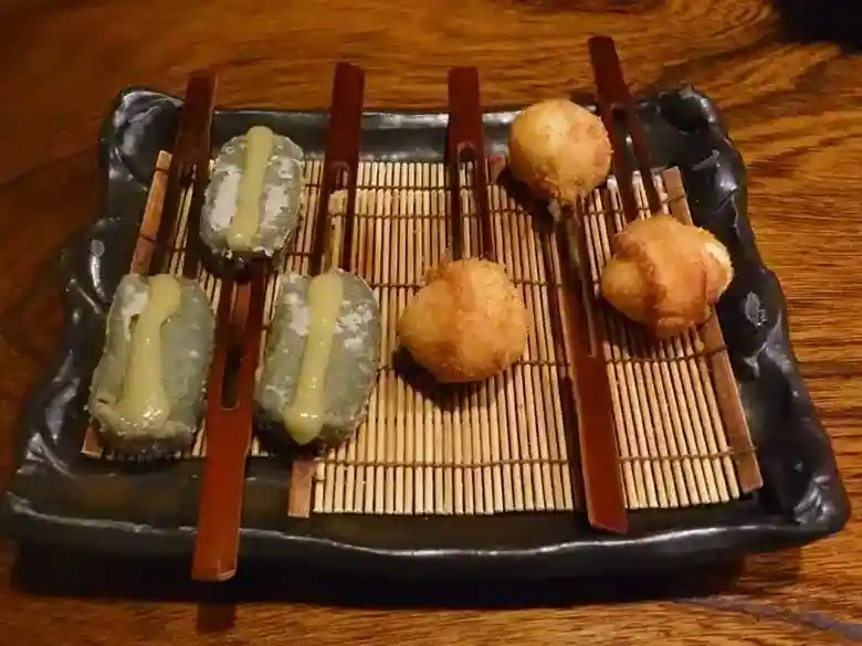 This photo shows the third plate of Kushiage: three Nama-fu Kushiage and three quail egg Kushiage served on a brown square plate.