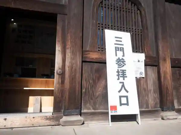Visitors can tour the interior of the Sanmon gate. This photo shows the entrance to the Sanmon gate. A signboard with the words "Sanmon Entrance" written in Japanese stands next to the door.