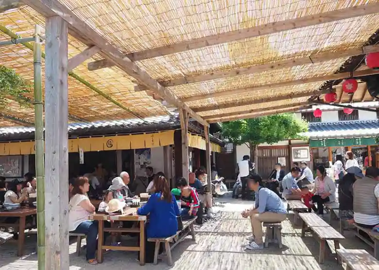 This photo shows the exterior of Fukusuke. Tables and chairs are set outside the store, and a bamboo screen covers the ceiling.