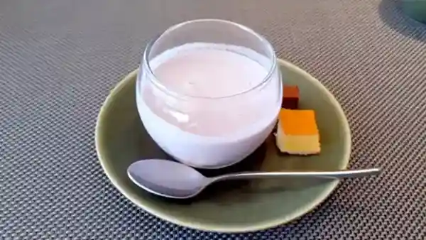 This photograph depicts tapioca yogurt and mini sponge cakes as dessert options for lunch. The light purple yogurt is served in a clear glass bowl.