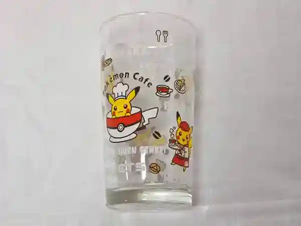 This photograph depicts the original glass from the Pokemon Cafe. The surface of the glass features illustrations of Pikachu as a chef and Pikachu as a waitress. The glass has a capacity of 500 mL.