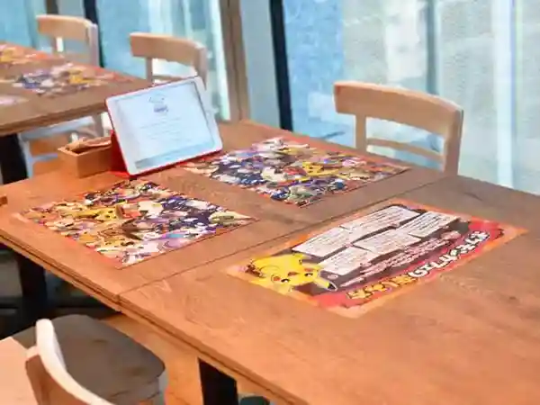 This photograph shows a table at the Pokémon Café. A tablet is provided for placing orders, and a Halloween-themed lunch mat is on the table. Additionally, there is a sheet explaining how to enjoy the Pokémon Café experience fully.