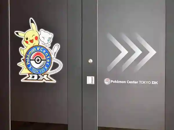 This photograph depicts the entrance to the Pokémon Center Tokyo DX. The black door features a depiction of Pikachu and Mew.