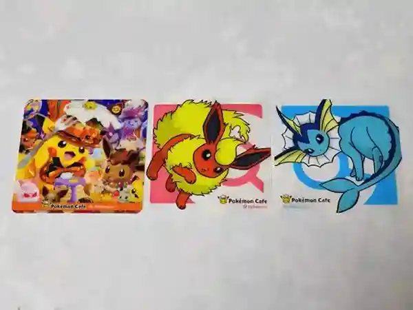 This picture displays three coasters that I received at the Pokemon Cafe. The coaster on the right features Pokemon dressed up for Halloween, while the other two coasters showcase Flareon and Vaporeon.