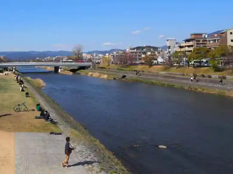 This photo is of the riverbank of the Kamo River. It was a beautiful day, and many people were enjoying the sun on the riverbank.