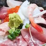This picture shows a Sashimi rice bowl served in a bowl of rice with thick slices of sashimi. Sashimi includes tuna, bonito, yellowtail, salmon roe, squid, octopus, and sweet shrimp.