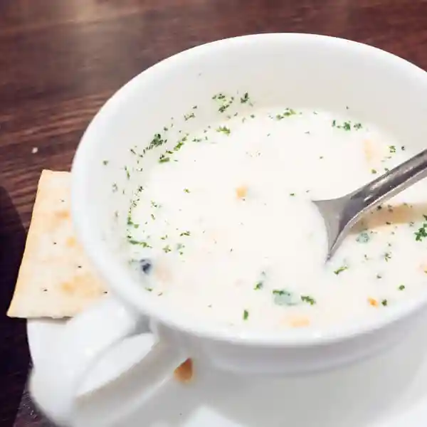 The photo shows the clam chowder in a white cup. It comes with two slices of cookies.