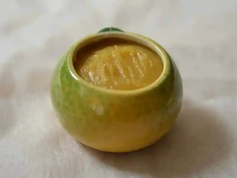 This photo shows the yuzu-shaped container with the lid removed. The container is filled with orange-colored yuzu miso.