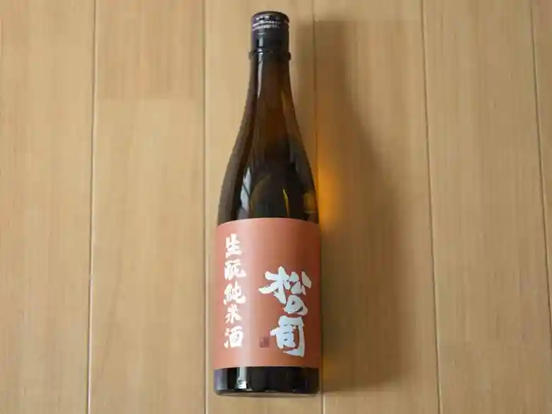 This photo shows a bottle of Matsu no Tsukasa's Nama-moto Junmai Nama-Genshu purchased at Izumiya Ichiko Shoten. The sake comes in a dark brown four-quart bottle.