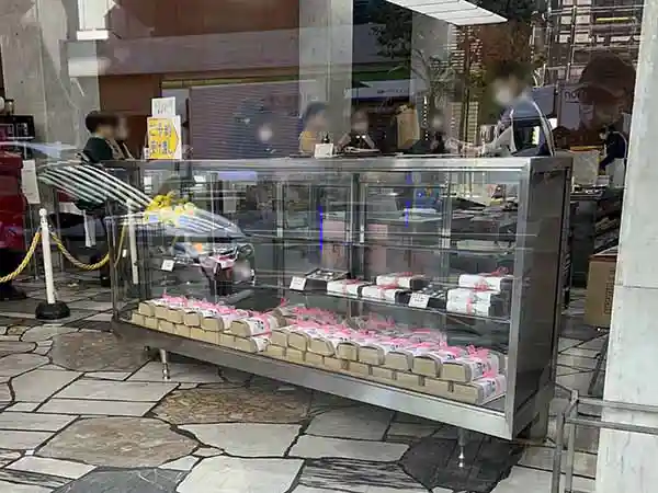 近江屋洋菓子店の店内を撮影した写真です。手前のショーケースには箱に包まれたシュトーレンが積まれています。購入する順番を待つ人の列ができています。