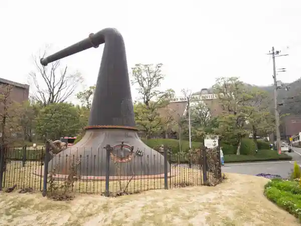 This photo shows a pot still used for distilling whiskey, displayed outdoors near the entrance to the Suntory Yamazaki Distillery.