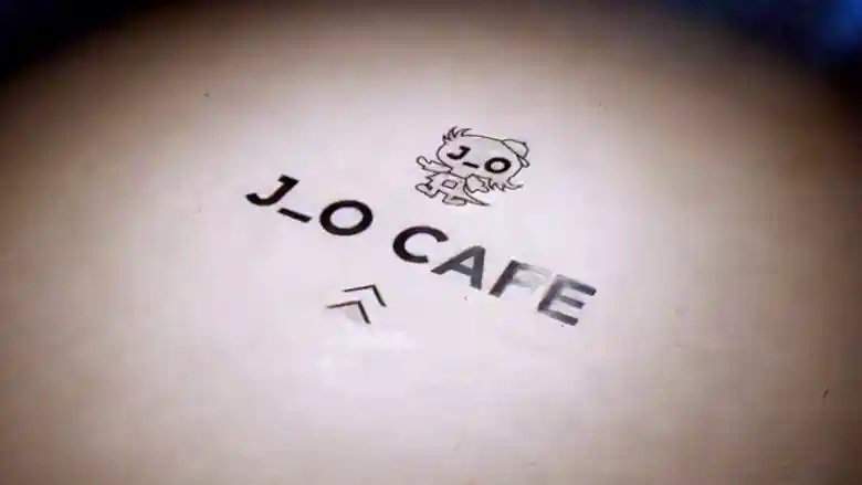 「J_O CAFE」へ向かう床に描かれたキャラクターとお店のロゴの写真です。