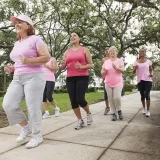 名の女性たちが速歩きしている写真です。皆さんがピンク色のTシャツを着て笑顔で速歩しています。