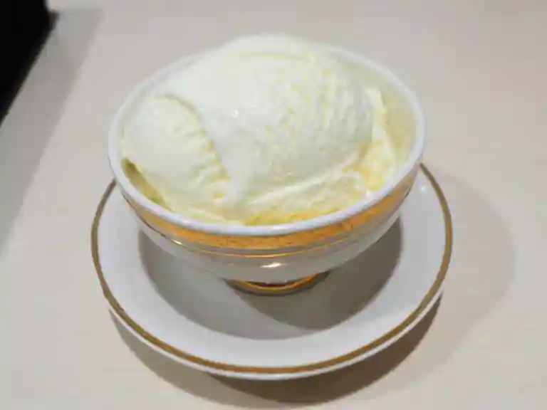 スノーロイヤル・バニラアイスクリームの写真です。コーヒーカップより一回り大きい器に入っています。薄わの縁が金メッキされていて高級感があります。アイスクリームは淡黄色です。口の中でふわっと溶けて濃厚なのにさっぱりとした味わいでした。