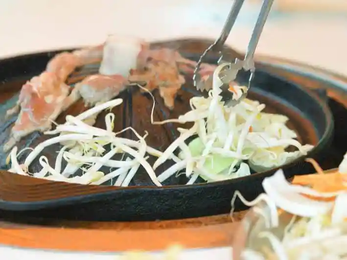 ジンギスカン鍋で野菜を焼いている写真です。野菜はジンギスカン鍋周縁の平らなところで焼きます。
