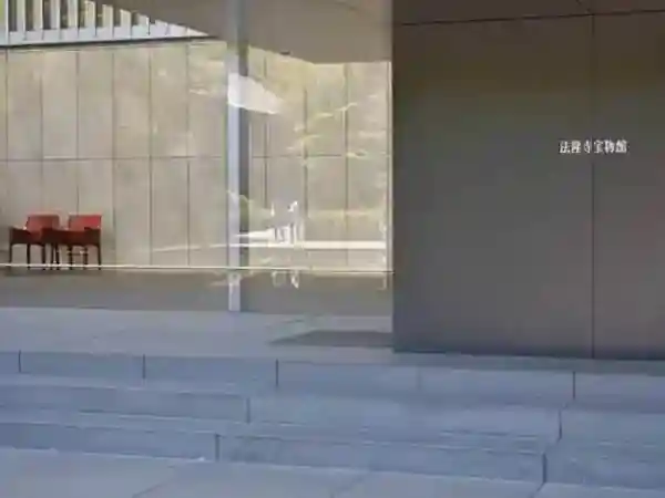 This photo captures the entrance to the Gallery of Horyuji Treasures. The front wall is made of transparent glass, offering a view of the entrance hall lined with armchairs inside.