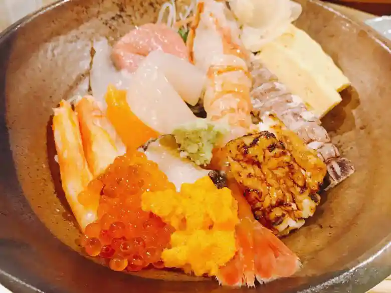 海鮮丼の写真です。海老とイクラ、うに、マグロ、イカ、シャコ、卵焼きが盛られています。
