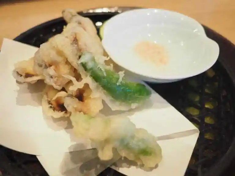 松茸の天ぷらの写真です。シシトウの天ぷらと梅塩が添えられています。