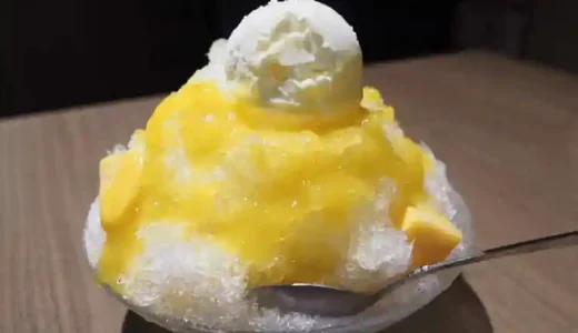 自家製かき氷の写真です。新潟で栽培した黄色いマンゴーシロップと北海道産の生乳で作ったアイスがかき氷の上に盛られています。
