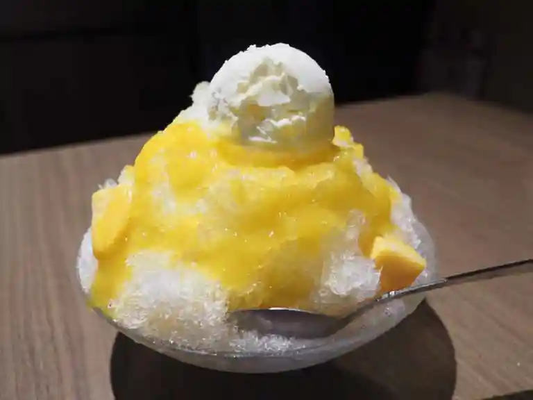 自家製かき氷の写真です。新潟で栽培した黄色いマンゴーシロップと北海道産の生乳で作ったアイスがかき氷の上に盛られています。