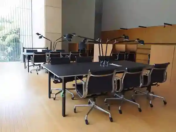 This photo displays the desks and chairs in the reference room on the second floor of the Gallery of Horyuji Treasures. The room features several sets of desks, each with six black chairs and three black lights.